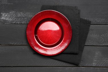 Koyu ahşap arka planda peçeteli kırmızı tabak