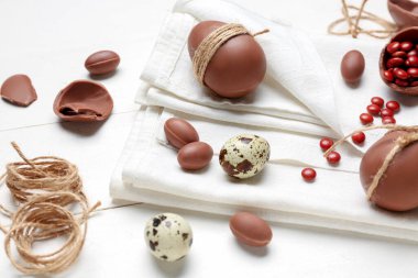 Şekerler, Paskalya yumurtaları ve beyaz ahşap arka planda iplik.