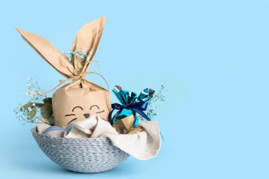 Mavi arka planda Paskalya tavşanı hediye paketi olan sepet.