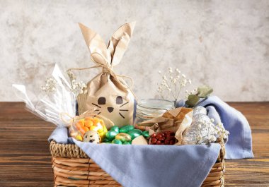 Paskalya tavşanı hediye paketi ve ahşap masada grunge duvarına yapıştırılmış şekerler.