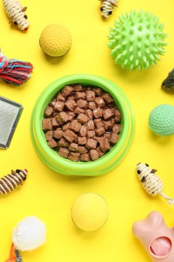 Farklı hayvan bakım aksesuarlarıyla kompozisyon ve sarı arka planda ıslak yemek.
