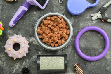 Arka planda bir kase ıslak yiyecek ve hayvan bakım aksesuarı olan kompozisyon