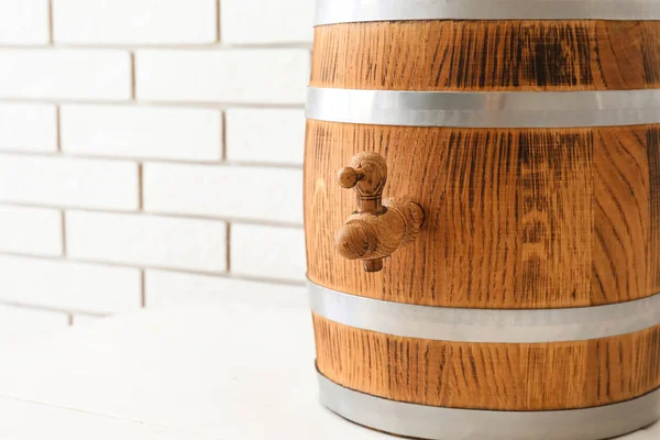 stock image Wooden barrel on table near light brick wall, closeup