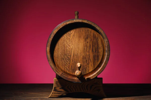 Wooden barrel on table near pink wall