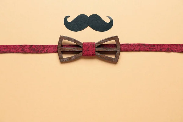 stock image Composition with stylish wooden bow tie and paper mustache on color background