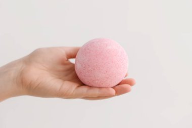 Arka planda pembe banyo bombası olan kadın.