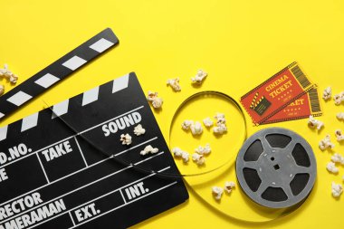 Filmin makarası, patlamış mısır ve sarı arka planda biletler.