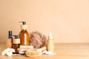 Kozmetik ürünleri şişeleri, masaj fırçaları ve ahşap masada sünger.