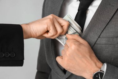 Businessman giving bribe on grey background, closeup
