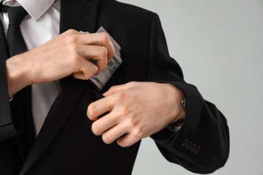 İşadamı, gri arka planda rüşveti cebine koydu, yakın plan.