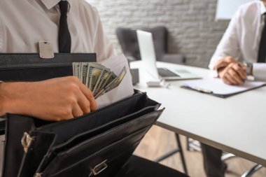 İş adamı ofiste evrak çantasından rüşvet alıyor, yakın plan.