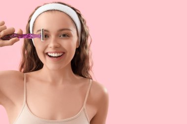 Pembe arka planda tıraş bıçağı olan genç bir kadın.