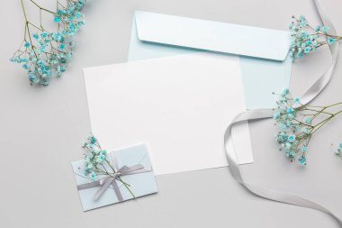 Beyaz arkaplanda boş kart, zarf ve güzel çigila çiçekleri olan kompozisyon