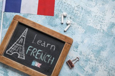 Üzerinde Learn FRENCH, kulaklıklar ve grunge arkaplanda Fransa bayrağı bulunan yazı tahtası