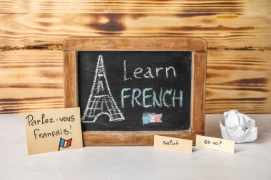 Tebeşir tahtası. Yazılı LEARN FRENCH, kelimeler ve ahşap duvarın yanındaki masada buruşmuş kağıt.