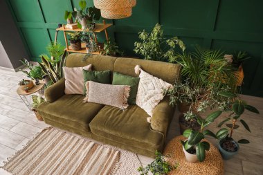 Oturma odasının içinde yeşil kanepe ve çiçekli.