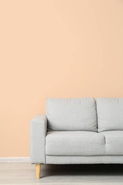 Bej duvarın yanındaki gri kanepe.