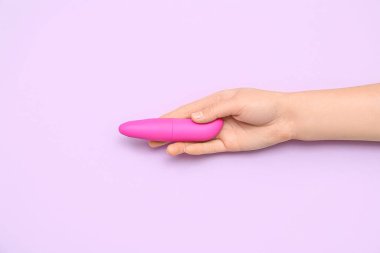 Leylak arka planında seks dükkanından pembe vibratörü olan kadın.