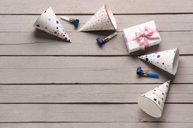 Parti şapkaları, düdükler ve hafif ahşap arka planda hediye kutusu olan kompozisyon