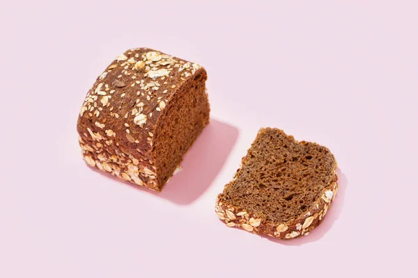 Pembe Arka Planda Çeşitli Tohumlarla Dilimlenmiş Çavdar Ekmeği — Stok fotoğraf