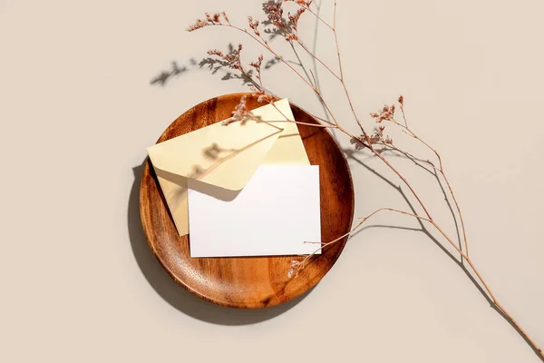 灰色の背景に空白のカード 封筒とドライフラワーを持つ木製のプレート — ストック写真