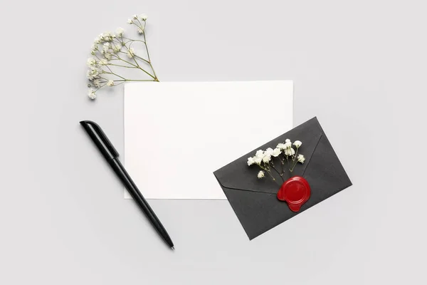 Composition with blank card, envelope, pen and gypsophila flowers on white background