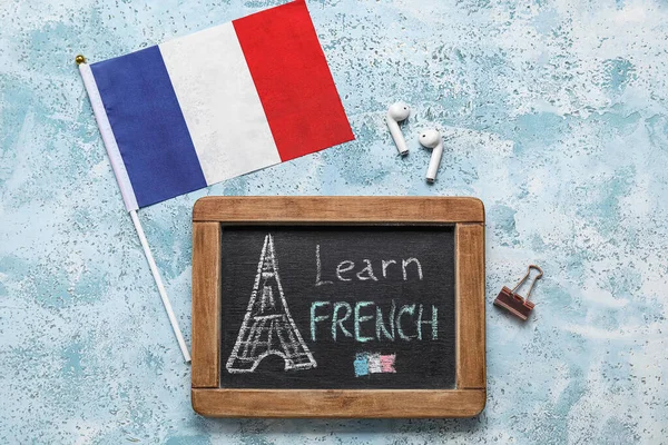 Üzerinde Learn FRENCH, kulaklıklar ve grunge arkaplanda Fransa bayrağı bulunan yazı tahtası