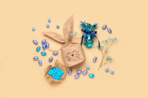 イースターバニーギフトバッグ キャンディー チョコレートの卵とベージュの背景にジプシーの花 — ストック写真