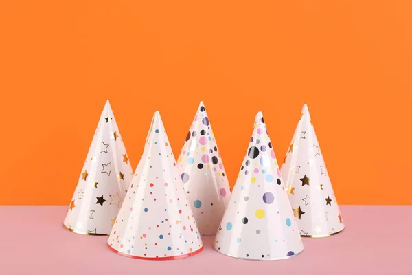 Different party hats on color background