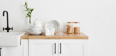 Mutfaktaki lavabonun yanında temiz sofra takımı var.