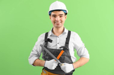 Yeşil arka planda dosyası ve çekici olan genç marangoz.