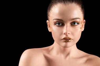 Young woman with golden glitter makeup on black background, closeup