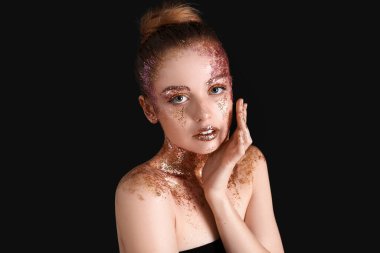 Young woman with glitter makeup on black background, closeup