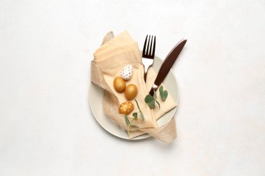 Table setting with Easter eggs, cutlery and plant branch on white background