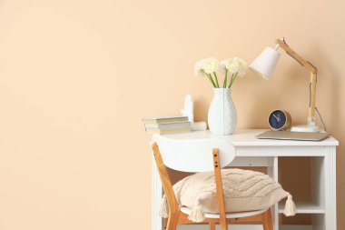 Vazoda ranunculus çiçekleri ve bej duvarın yanında lamba olan işyeri