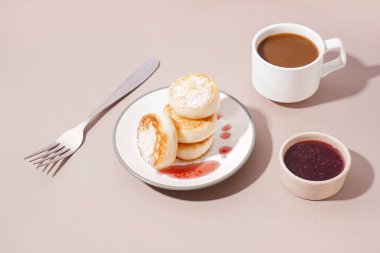 Lezzetli süzme peynirli krep, çilek reçeli ve arka planda bir fincan kahve.