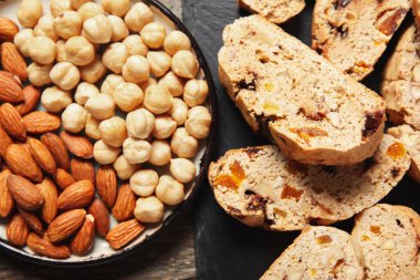 Lezzetli bisküviler ve ahşap arka planda bir tabak fındık, yakın plan.