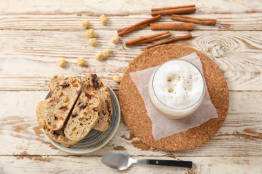 Lezzetli bisküviler, fındıklar, tarçın ve beyaz ahşap arka planda bir fincan kahve.