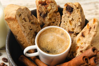 Kahveli kase, lezzetli bisküviler ve beyaz ahşap arka planda tarçın.
