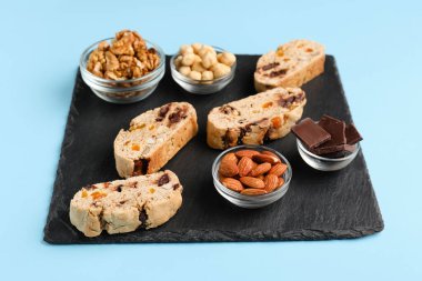 Lezzetli bisküviler, fındıklar ve çikolatalar mavi arka planda.