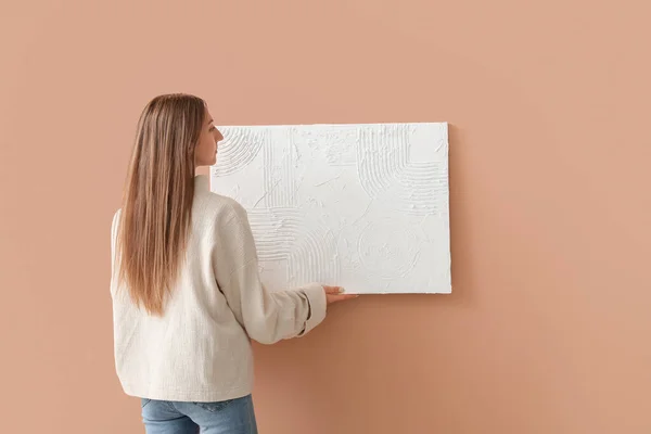 Молодая Женщина Вешает Картину Бежевую Стену — стоковое фото