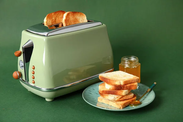 面包片在现代烤面包机 蜂蜜罐和美味的面包绿色背景 — 图库照片