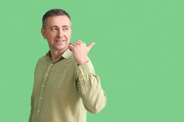 Dojrzały Mężczyzna Koszuli Wskazując Coś Zielonym Tle — Zdjęcie stockowe