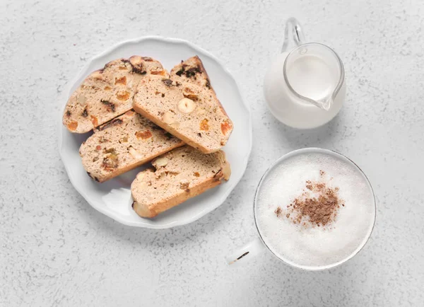 Delicious biscotti cookies, pitcher with milk and cup of coffee on white grunge background