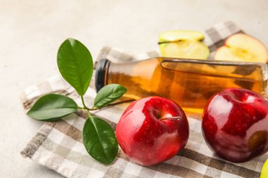 Cam şişe taze elma sirkesi ve beyaz masada meyveler.