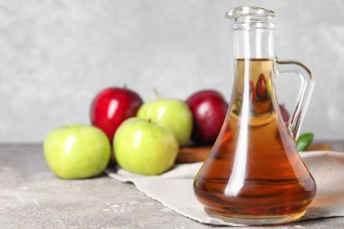 Cam şişe taze elma sirkesi ve grunge masasında meyveler.