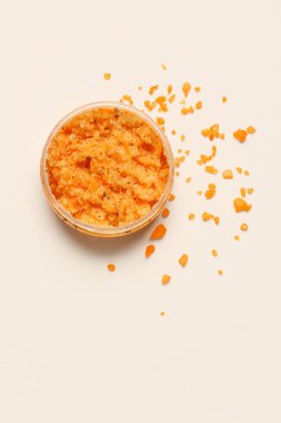 Jar of body scrub and sea salt on light background