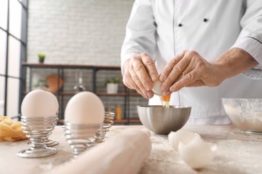 Erkek aşçı hamur işi yapıyor. Mutfaktaki masada, yakın plan.