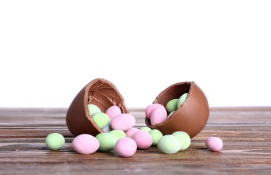 Çikolatalı Paskalya yumurtası ve şeker beyaz arka plana karşı ahşap masada.