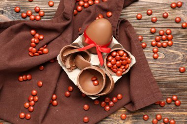 Çikolatalı Paskalya yumurtaları ve kahverengi ahşap arka planda şekerler.